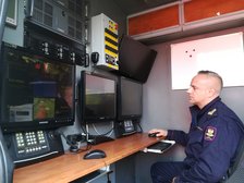 Funkcjonariusz Straży Ochrony kolei prezentuje wnętrze Mobilnego Centrum Monitoringu, czyli specjalistycznego samochodu służbowego wyposażonego w system kamer dziennych i nocnych.